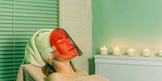 Woman using red light therapy mask.